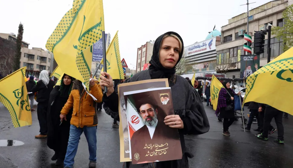 An Iranian woman holds an image of the new Iranian supreme leader Ayatollah Mojtaba Khamenei, who was nominated after the assassination of his father in a US-Israeli attack on February 28, as she takes part in the Al-Quds (Jerusalem) Day rally, a commemoration in support of the Palestinian people on the last Friday of the Islamic holy month of Ramadan, in Tehran on March 13, 2026. On February 28, Israel and the United States launched strikes on Iran, killing its supreme leader Ayatollah and triggering a war that spread across the Middle East. (Photo by AFP)/