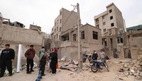 Iranians gather in front of destroyed buildings following a military strike on the Iranian capital Tehran on March 15, 2026. Iran's Foreign Minister said in an interview published on March 15, that the war pitting his country against the United States and Israel will only end when Tehran can be certain it will not be restarted. On February 28, Israel and the United States launched strikes on Iran, killing its supreme leader Ayatollah and triggering a war that spread across the Middle East. (Photo by Atta KENARE/AFP)/