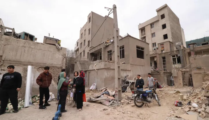 Iranians gather in front of destroyed buildings following a military strike on the Iranian capital Tehran on March 15, 2026. Iran's Foreign Minister said in an interview published on March 15, that the war pitting his country against the United States and Israel will only end when Tehran can be certain it will not be restarted. On February 28, Israel and the United States launched strikes on Iran, killing its supreme leader Ayatollah and triggering a war that spread across the Middle East. (Photo by Atta KENARE/AFP)/