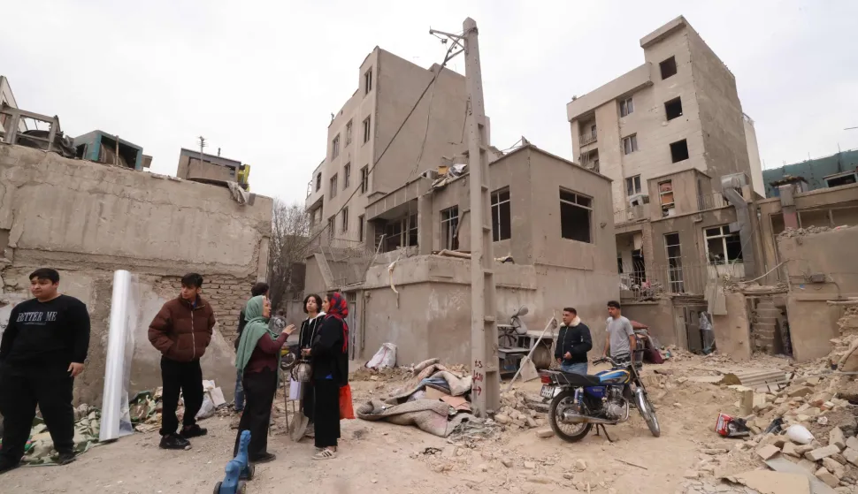 Iranians gather in front of destroyed buildings following a military strike on the Iranian capital Tehran on March 15, 2026. Iran's Foreign Minister said in an interview published on March 15, that the war pitting his country against the United States and Israel will only end when Tehran can be certain it will not be restarted. On February 28, Israel and the United States launched strikes on Iran, killing its supreme leader Ayatollah and triggering a war that spread across the Middle East. (Photo by Atta KENARE/AFP)/