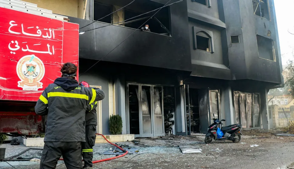 Firefighters stand outside a building that caught fire following Israeli bombardment on the town of Abbassiyeh near Lebanon's southern coastal city of Tyre on March 18, 2026. Israel's army issued an evacuation order late on March 17 for Tyre and surrounding areas as it said it struck Hezbollah targets in the country and the militants claimed a wave of attacks. Lebanon was drawn into the Middle East war on March 2 when pro-Iran Hezbollah launched rockets towards Israel in response to US-Israeli strikes that killed Iran's supreme leader. (Photo by Kawnat HAJU/AFP)/