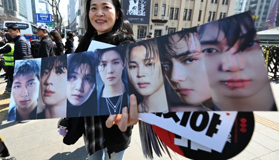 A woman holds a banner showing pictures of BTS members as BTS fans arrive at the venue of the comeback concert of K-pop boy group BTS in downtown Seoul on March 21, 2026. The world's biggest boy band BTS reunites on March 21, for an open-air comeback concert in the heart of Seoul, expected to draw around 250,000 people and beamed live across the globe. (Photo by Jung Yeon-je/AFP)