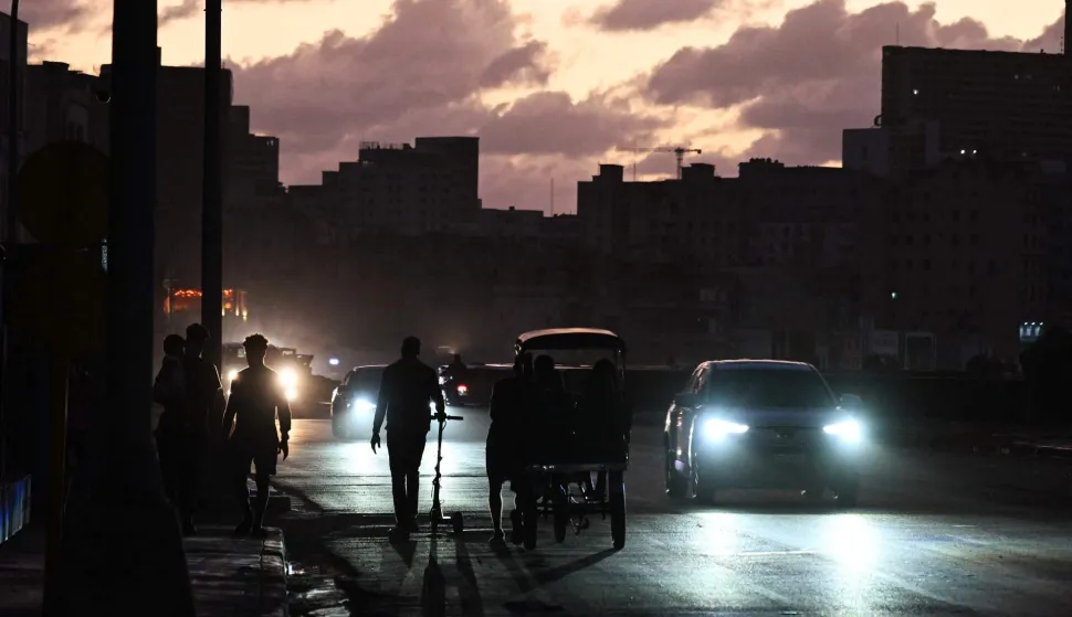 People transit on a street without power during a nation wide blackout in Havana on March 21, 2026. A power outage struck the entire island of Cuba on March 21, 2026, the energy ministry said, in the second nationwide blackout in less than a week as its grid struggles under a US oil blockade. (Photo by Yamil LAGE/AFP)