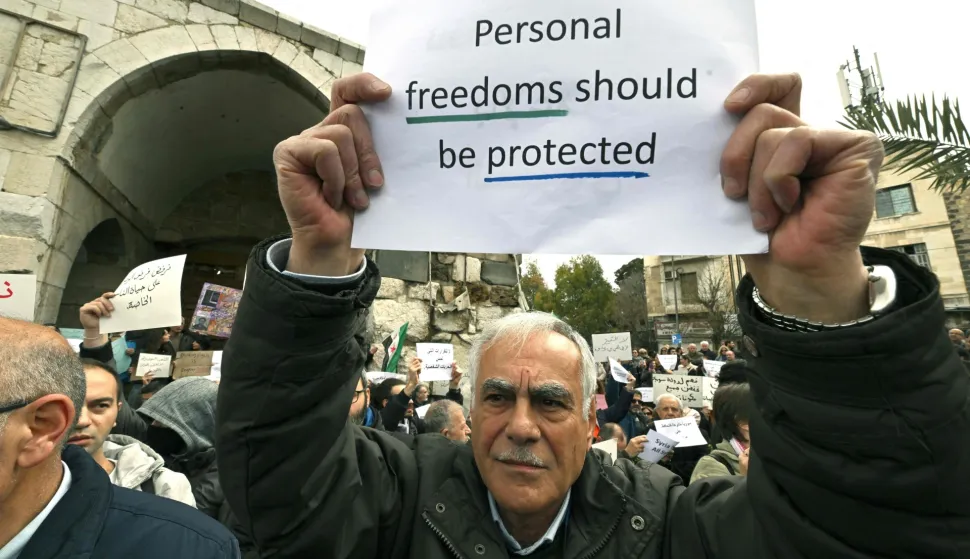 Syrians hold a silent sit-in, called for by civil society, Christians, and shop owners affected by an official decision banning the sale of alcoholic beverages except in specific locations and demanding an end to state interference in personal freedoms and the sectarian division of society, in Bab Touma in Damascus on March 22, 2026. Syria's capital on March 16, 2026, restricted the sale of alcoholic beverages to select Christian neighbourhoods, the latest incident hinting at increasing social conservatism under Islamist authorities. (Photo by LOUAI BESHARA/AFP)