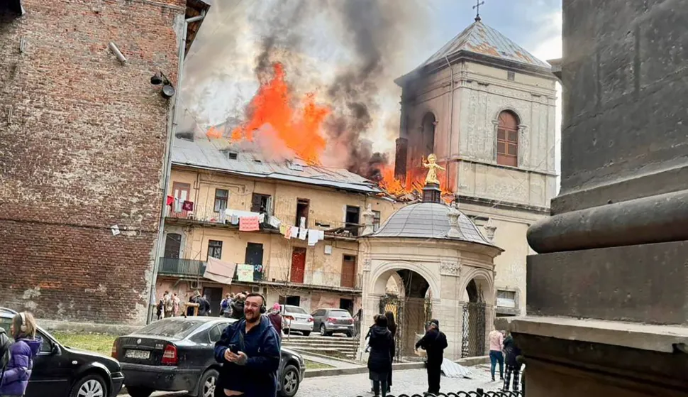 In this handout photograph taken and posted on the official Telegram channel of Lviv mayor on March 24, 2026, people stand next to a burning building following an air attack in Lviv, amid the Russian invasion of Ukraine. A barrage of Russian missiles and drones killed five people and wounded more than two dozen across Ukraine on March 24, 2026 in the largest attack in weeks, officials said. (Photo by Handout/TELEGRAM /@andriysadovyi/AFP)/RESTRICTED TO EDITORIAL USE - MANDATORY CREDIT "AFP PHOTO/OFFICIAL TELEGRAM CHANNEL OF LVIV MAYOR ANDRIY SADOVY" - HANDOUT - NO MARKETING NO ADVERTISING CAMPAIGNS - DISTRIBUTED AS A SERVICE TO CLIENTS
