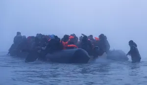 Smugglers assist migrants to board a boat in an attempt to cross the English Channel off the beach of Gravelines, northern France, on March 4, 2026. (Photo by Sameer Al-DOUMY/AFP)