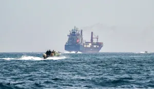 (FILES) A boat approaches the St Kitt's and Nevis-flagged container ship Marsa Victory while crusing in the waters of the Strait of Hormuz off the coast of Khasab in Oman?s northern Musandam peninsula on June 25, 2025. (Photo by Giuseppe CACACE/AFP)