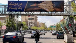 TOPSHOT - A billboard with the Persian caption "every missile has a message" depicting an Iranian combat drone inscribed with text the "pn behalf of the martyrs and the oppressed and fasting people of homeland Iran" is displayed along a road used by motorists in Tehran on March 30, 2026. Israel and Iran exchanged more missile fire on March 30 as concerns that the US might escalate the Middle East conflict by launching ground raids against the Islamic republic's Gulf islands sent oil prices soaring. (Photo by ATTA KENARE/AFP)/