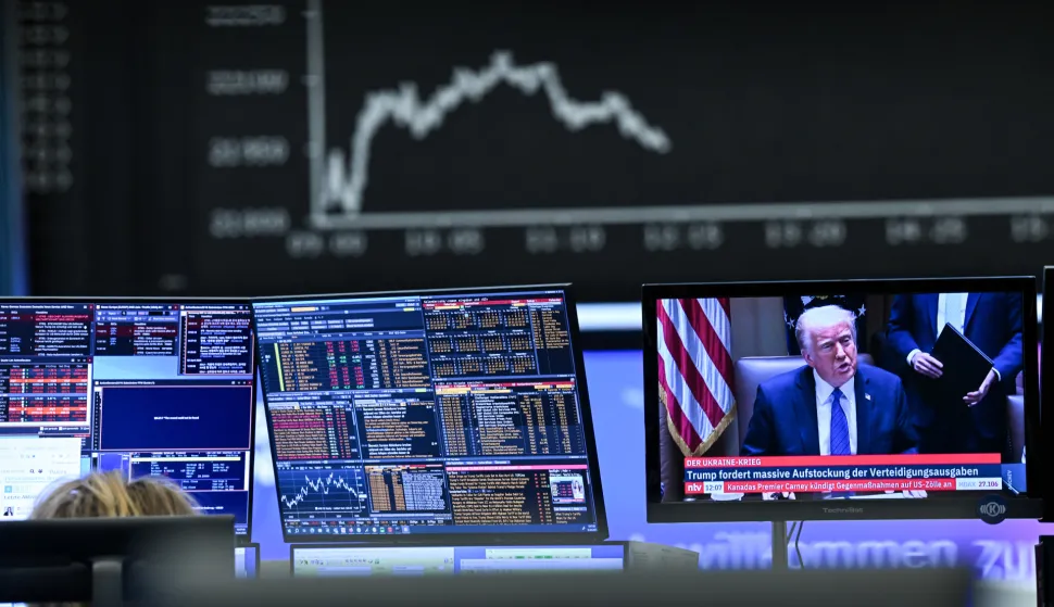 03 April 2025, Hesse, Frankfurt/Main: Behind a television monitor showing US President Donald Trump, the display board with the Dax curve shows falling share prices. The tariff package announced by US President Trump has pushed share prices sharply into the red. Photo: Arne Dedert/dpa Photo: Arne Dedert/DPA