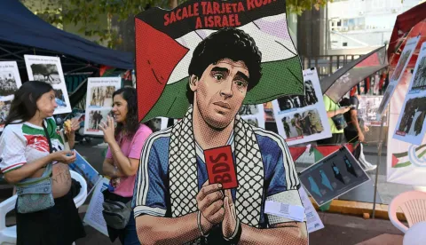 A cutout depicting Argentine football legend Diego Maradona holding a red card and a sign reading ?Give Israel a red card? is displayed during a demonstration in front of the Israeli Embassy in Buenos Aires on March 24, 2026, as part of the mobilization marking the 50th anniversary of the military coup. In Argentina, March 24th is a day of mourning, marches and political disputes. Fifty years on from the coup d?etat, thousands of people are taking to the streets again to commemorate the victims of a dictatorship that the government of far-right leader Javier Milei is seeking to rewrite. (Photo by Juan Mabromata/AFP)