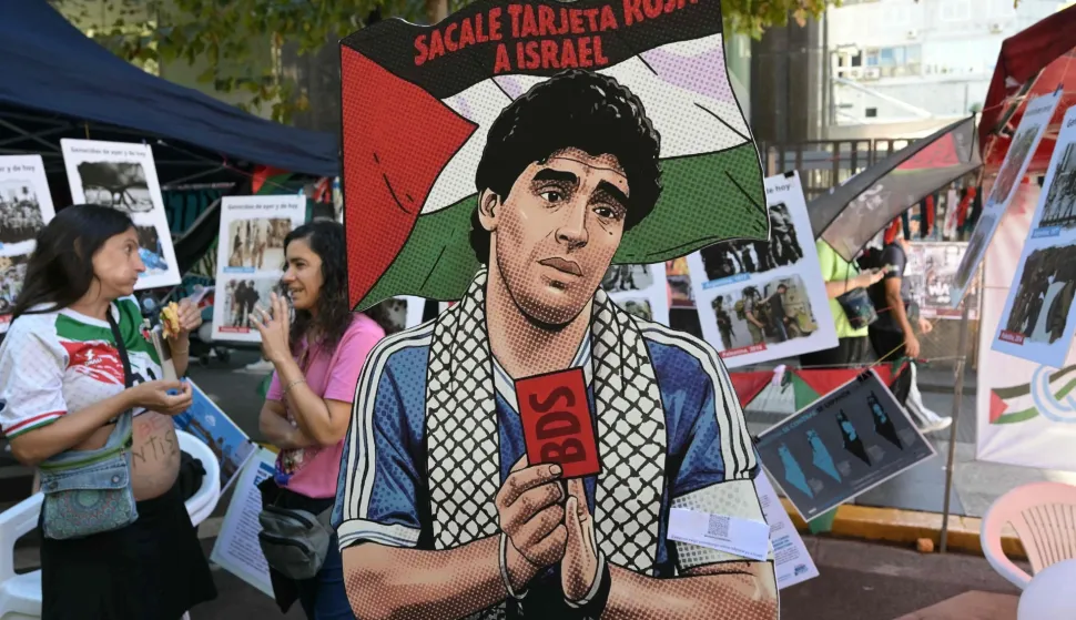 A cutout depicting Argentine football legend Diego Maradona holding a red card and a sign reading ?Give Israel a red card? is displayed during a demonstration in front of the Israeli Embassy in Buenos Aires on March 24, 2026, as part of the mobilization marking the 50th anniversary of the military coup. In Argentina, March 24th is a day of mourning, marches and political disputes. Fifty years on from the coup d?etat, thousands of people are taking to the streets again to commemorate the victims of a dictatorship that the government of far-right leader Javier Milei is seeking to rewrite. (Photo by Juan Mabromata/AFP)