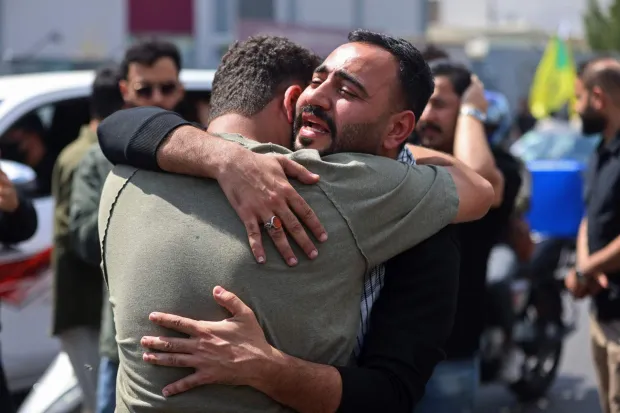 Mourners react before the mourning procession for a member of Iraq's pro-Iran paramilitary group Hezbollah Brigades (Kataeb Hezbollah) who was killed the previous day in a strike in Basra, during the funeral in Baghdad on April 8, 2026. Iraqi armed factions loyal to Iran and operating under the banner of the "Islamic Resistance in Iraq" announced a two-week halt to attacks they had launched since the start of the war in the Middle East against "enemy bases" in Iraq and the region. The announcement came shortly after Washington and Tehran declared a ceasefire for the same period. (Photo by AHMAD AL-RUBAYE/AFP)