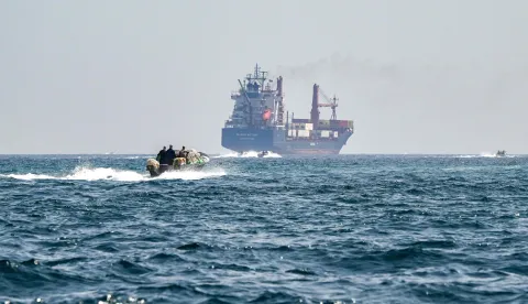 (FILES) A boat approaches the St Kitt's and Nevis-flagged container ship Marsa Victory while crusing in the waters of the Strait of Hormuz off the coast of Khasab in Oman?s northern Musandam peninsula on June 25, 2025. (Photo by Giuseppe CACACE/AFP)