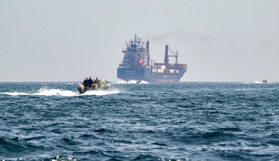 (FILES) A boat approaches the St Kitt's and Nevis-flagged container ship Marsa Victory while crusing in the waters of the Strait of Hormuz off the coast of Khasab in Oman?s northern Musandam peninsula on June 25, 2025. (Photo by Giuseppe CACACE/AFP)