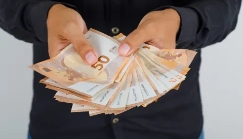 Young man in black shirt holding euro banknotes, front view.novac freepik