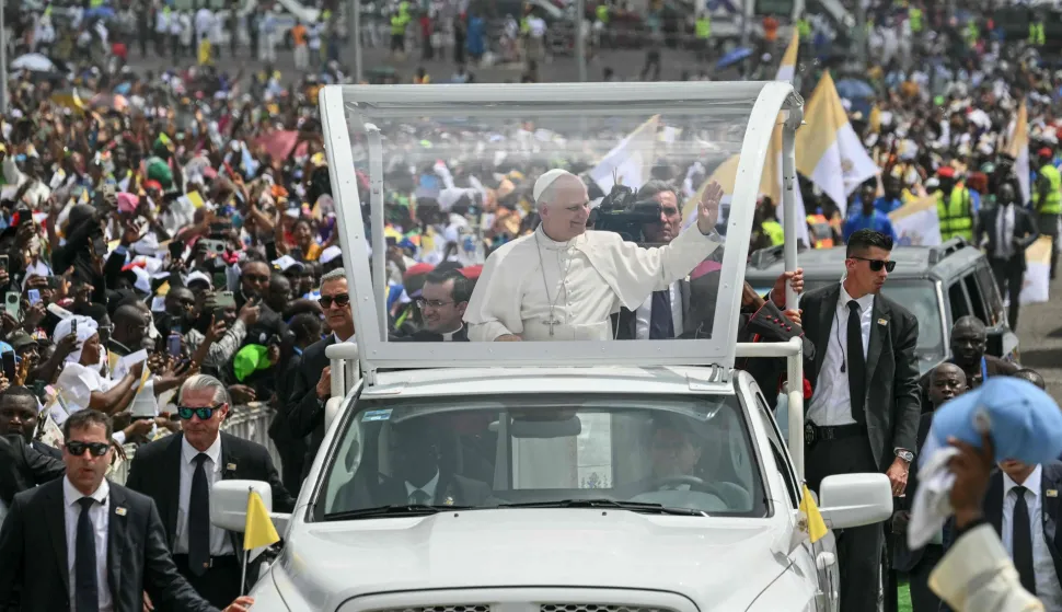 Pope Leo XIV (C) waves to the crowd from the Popemobile as he arrives to lead the Holy Mass at the area in front of Japoma Stadium in Douala on the fifth day of an 11-day apostolic journey to Africa, on April 17, 2026. (Photo by Alberto PIZZOLI/AFP)