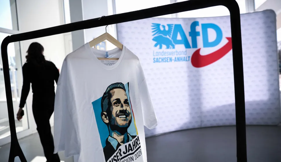 Merchandise of the far-right Alternative for Germany (AfD) party, including a shirt with the portrait of the party's top candidate for regional elections in Saxony-Anhalt, is on display in the Hyparschale hall in Magdeburg, eastern Germany, during a regional party congress of the far-right Alternative for Germany (AfD), on April 11, 2026. The AfD in the eastern federal state of Saxony-Anhalt holds a two-day party convention to prepare regional elections scheduled for September 6, 2026. (Photo by RONNY HARTMANN/AFP)
