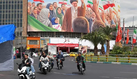Motorists ride past a giant billboard of slain Iranian supreme leader Ayatollah Ali Khamenei at the Valiasr Square in Tehran on April 19, 2026. The strategic Strait of Hormuz was again closed on April 19 in the stand-off between Iran and the United States, with Iran's powerful parliament speaker signalling a final peace deal remained "far" off despite some movement in negotiations. (Photo by ATTA KENARE/AFP)/