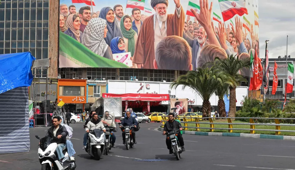 Motorists ride past a giant billboard of slain Iranian supreme leader Ayatollah Ali Khamenei at the Valiasr Square in Tehran on April 19, 2026. The strategic Strait of Hormuz was again closed on April 19 in the stand-off between Iran and the United States, with Iran's powerful parliament speaker signalling a final peace deal remained "far" off despite some movement in negotiations. (Photo by ATTA KENARE/AFP)/