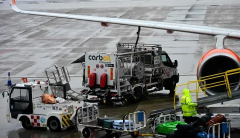 A worker loads luggage onto an Easyjet aircraft as a fuel truck "CarbOil" services the plane at Milan's Malpensa Airport on April 13, 2026. The European Commission said April 14, 2026 it fears Europe could face jet fuel supply issues "in the near future" with no end in sight to the Iran war roiling global energy markets. (Photo by Stefano Rellandini/AFP)
