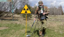 epa09152965 A dosimetrist walks past the radiation sign at the Chernobyl zone, Ukraine, 22 April 2021. Ukraine will mark the 35th anniversary of Chernobyl tragedy on 26 April 2021. The explosion of reactor 4 of the Chernobyl nuclear power plant in the early hours of 26 April 1986 is still regarded as the worst nuclear disaster no date. EPA/SERGEY DOLZHENKO