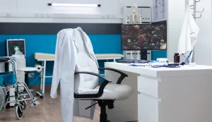 Computer with covid19 illustration on screen standing on desk in empty office room during global pandemic. Modern hospital room equipped with professional medical instruments. Virus cell imageobiteljska medicina ordinacija doktor liječnik freepik