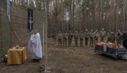 Military chaplain Mykola Bahirov prays with Ukrainian military members of the 33rd separate mechanised brigade next to traditional cakes and other food to celebrate Orthodox Easter, in the Kharkiv region, on April 12, 2026, amid the Russian invasion of Ukraine. A member of the Greek Catholic faith, this 39-year-old man was serving as a diocesan secretary when Russia launched its full-scale invasion of Ukraine in February 2022. It was at a soldier's funeral, when he saw the terror in the soldier's daughters, that Mykola Bahirov decided to become a chaplain: rather than accompany them in death, he would, while they were still alive, stay close to the Ukrainian soldiers fighting against the Russian invader. (Photo by Roman PILIPEY/AFP)