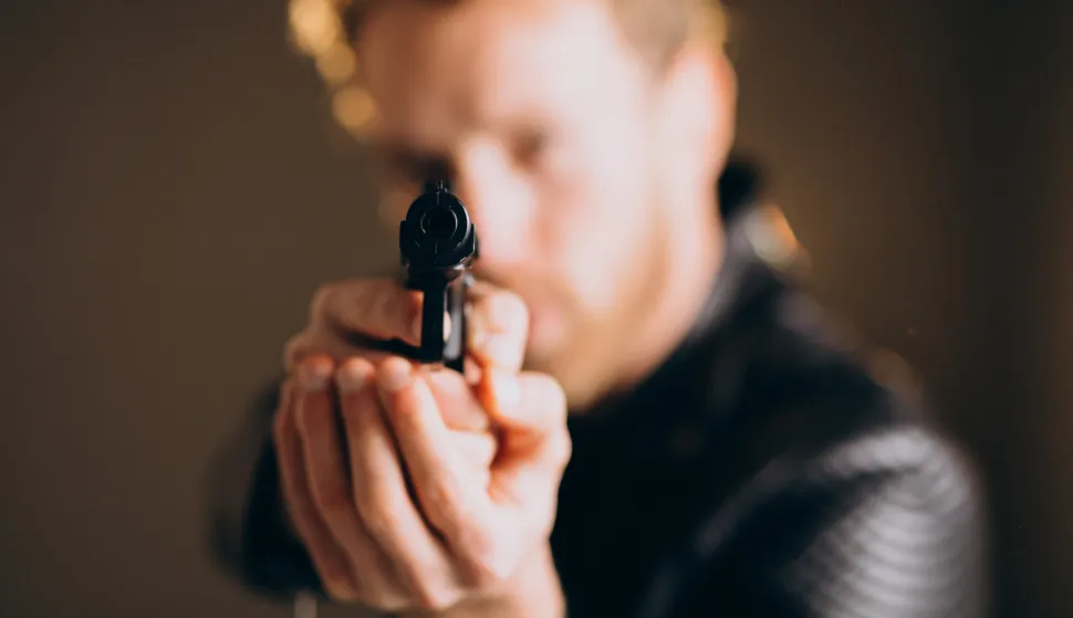 Handsome man actor posing in studio with weaponilustracija, crna kronika, kriminal, kriminalac, pravosuđe, ubojstvo, smrt, pi&scaron;tolj, oružjefreepik 