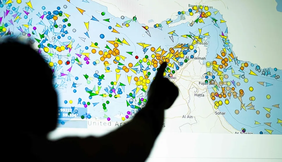 TOPSHOT - A photo illustration taken in Nicosia on May 4, 2026, shows a person in front of a large screen displaying vessel movements in the Strait of Hormuz on a ship-tracking website. Iran's navy fired 'warning shots' at US warships in the Strait of Hormuz on May 4, state media said, after the American military sent cruisers into the Gulf as part of a plan to help trapped commercial vessels leave. Earlier, US President Donald Trump had announced a plan to guide ships from neutral countries out of the Gulf, saying it was a humanitarian effort to help their stranded crews. (Photo by AFP)