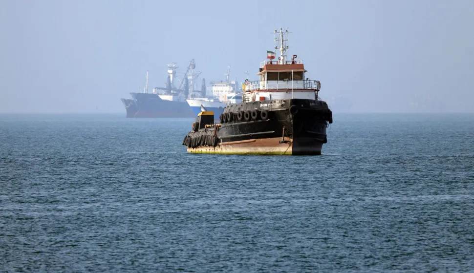 TOPSHOT - In this picture obtained from Iran's ISNA news agency on May 4, 2026, the Iran-flagged tugboat Basim sails near a ship anchored in the Strait of Hormuz off Bandar Abbas in southern Iran. Iran's Revolutionary Guards on May 4 denied that any commercial ships had crossed the Strait of Hormuz, after the US military earlier said two US-flagged merchant vessels had transited through the vital waterway. (Photo by Amirhossein KHORGOOEI/ISNA/AFP)/