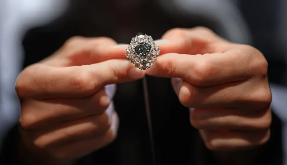 (FILES) A Christie?s member of staff shows a triangular-shaped fancy vivid blue-green diamond weighing 5.50 carats, known as "The Ocean Dream", during a press preview at Christie?s auction house in Geneva, on May 7, 2026. A vivid blue-green diamond of 5.50 carats, the largest known to date, was sold for more than $17 million on Wednesday in Geneva, exceeding expectations, Christie's announced. (Photo by Fabrice COFFRINI/AFP)