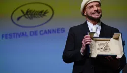 US director, screenwriter and writer John Travolta (L) receives an honorary Palm d'Or award prior to the screening of the film "Propeller One-Way Night Coach" at the 79th edition of the Cannes Film Festival in Cannes, southern France on May 15, 2026. (Photo by Olivier CHASSIGNOLE/AFP)