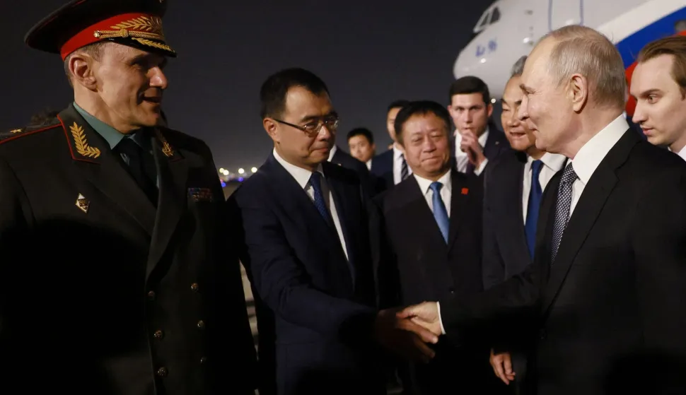 In this pool photograph distributed by the Russian state agency Sputnik, Russia's President Vladimir Putin is welcomed by Chinese Foreign Minister Wang Yi and other officials upon his arrival at Beijing Capital Airport in Beijing late on May 19, 2026. (Photo by Vladimir SMIRNOV/POOL/AFP)