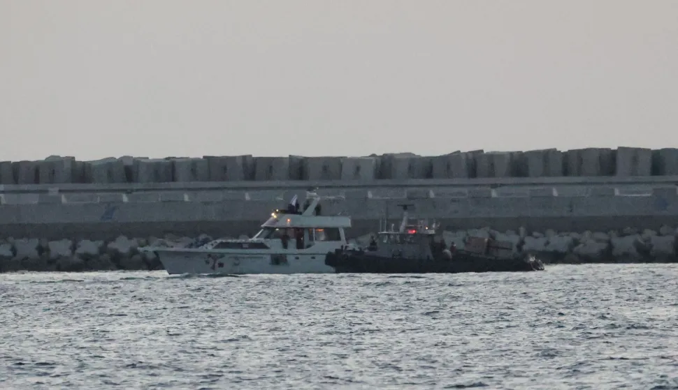 A boat bearing symbols of one of the vessels belonging to the Gaza-bound aid flotilla (L) and intercepted by the Israeli navy, is motored towards the Israeli port of Ashdod, about 40 kilometres south of Tel Aviv, on May 19, 2026. The Global Sumud Flotilla vessels are the latest in a string of attempts by activists to breach Israel's blockade of the Palestinian territory, with the last convoy intercepted by Israeli forces. Israel controls all entry points into Gaza, which has been under an Israeli blockade since 2007. During the Gaza war, triggered by Hamas's October 2023 attack on Israel, the territory has suffered severe shortages of food, medicine and other essential supplies, with Israel at times halting aid deliveries entirely. The Israeli ministry rejected claims that Gaza was facing aid shortages. (Photo by Jack GUEZ/AFP)