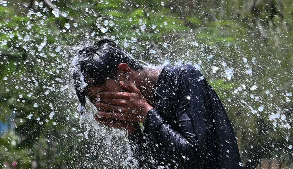 A man cools off on a hot summer day, at a park in Karachi on May 12, 2026. (Photo by Asif HASSAN/AFP)