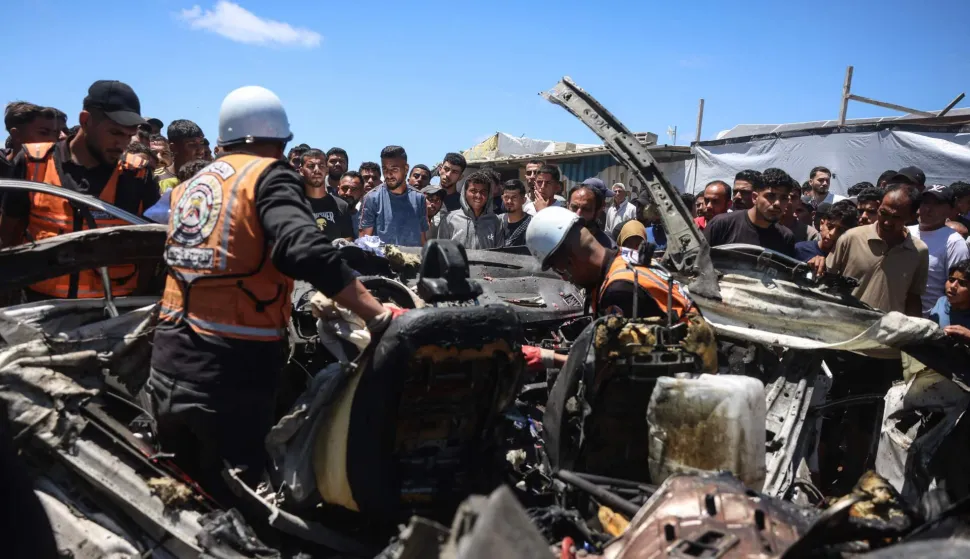 EDITORS NOTE: Graphic content/Members of the Palestinian civil defence inspect the wreckage of a vehicle targeted by an Israeli strike as bystanders watch in Khan Yunis in the southern Gaza Strip on May 26, 2026. Since October 10, a fragile US-sponsored truce in Gaza has largely halted the fighting between Israeli forces and Hamas, but both sides have alleged frequent violations. (Photo by Bashar Taleb/AFP)