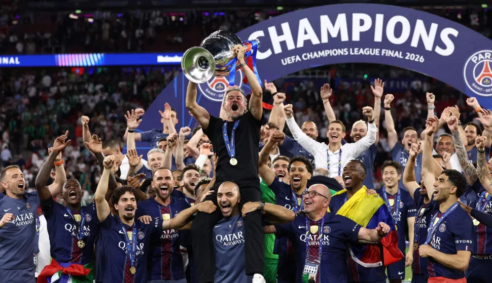 Paris Saint-Germain's Spanish head coach Luis Enrique (C) lifts the trophy as he celebrates with his players after winning the UEFA Champions League final football match between Paris Saint-Germain (PSG) and Arsenal FC at the Puskas Arena in Budapest on May 30, 2026. (Photo by FRANCK FIFE/AFP)