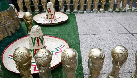TOPSHOT - Souvenirs shaped like the FIFA World Cup trophy and traditional Mexican hats are displayed for sale on a street in Mexico City on June 8, 2026. (Photo by Yuri CORTEZ/AFP)