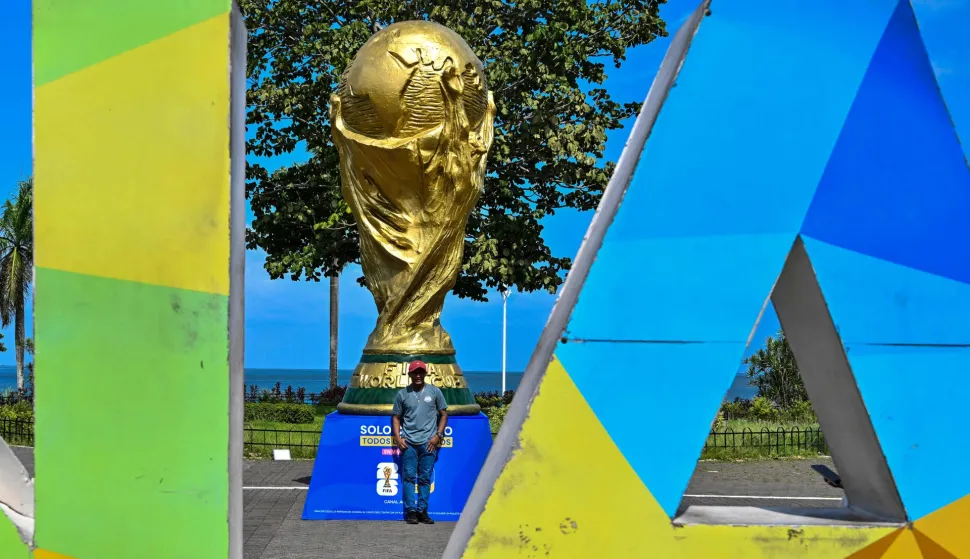 A man poses for a photo in front a giant replica of the FIFA World Cup trophy at the Cinta Costera in Panama City on May 13, 2026. Panama will play in the FIFA World Cup hosted by the United States, Mexico, and Canada from June 11 to July 19, 2026. (Photo by Martin BERNETTI/AFP)
