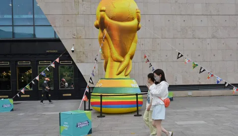 People walk past an effigy featuring the World Cup trophy at a shopping center in Beijing on June 12, 2026. (Photo by ADEK BERRY/AFP)