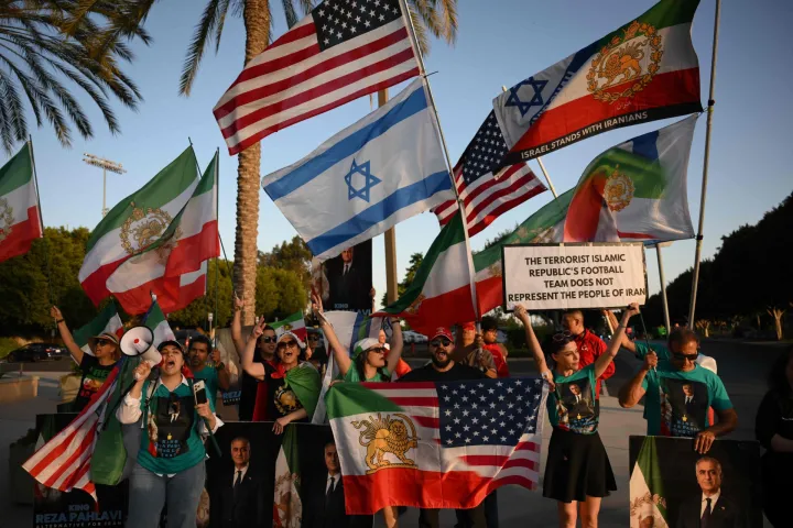 People hold pre-revolutionary Iranian flags as they protest the Iranian regime outside Carson Sports Park before Iran?s training session in Los Angeles on June 14, 2026, on the eve of the 2026 World Cup football match between Iran and New Zealand. (Photo by Patrick T. Fallon/AFP)
