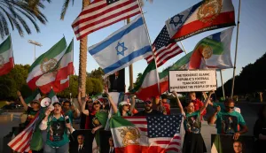 People hold pre-revolutionary Iranian flags as they protest the Iranian regime outside Carson Sports Park before Iran?s training session in Los Angeles on June 14, 2026, on the eve of the 2026 World Cup football match between Iran and New Zealand. (Photo by Patrick T. Fallon/AFP)