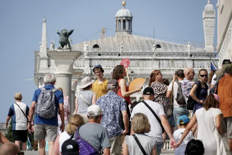 epa11515174 A tour guide (C), using a radio microphone to communicate, leads a group of visitors to St. Mark's Square, in Venice, Italy, 01 August 2024. Venice's city administration from 01 August will start enforcing new rules that limit tourist groups' sizes to 25 people and prohibit the use of loudspeakers by tour guides, seeking to reduce the impact of over-tourism on the city's residents. EPA/ANDREA MEROLA