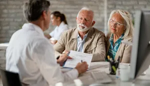 Senior couple consulting with healthcare worker about their insurance policy while having a meeting at clinic.banka novac osiguranje ilustracija stariji par umirovljenik umirovljenici freepik