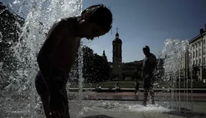 A child cools off in a fountain in Lyon on May 27, 2026 as a heatwave hits France. France is experiencing an "unprecedented" heatwave in May, with 13 departments on orange heat alert and peaks forecast at 38?39?C. National weather service Meteo France on May 26, 2026, registered a new nationwide monthly temperature record with a national heat index, which measures the average temperature across the country, of 24.8C surpassing Monday's 24.6C. (Photo by Jeff PACHOUD/AFP)