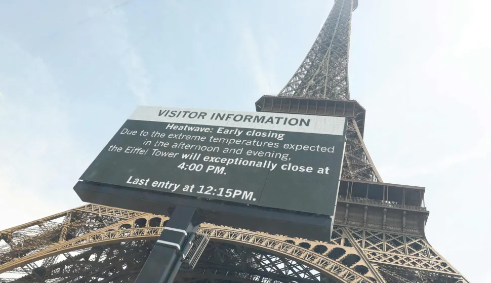 This photograph taken through a window shows the Eiffel Tower with a giant screen announcing its early closing due to heatwave in Paris on June 23, 2026. A deadly heatwave has battered France since last week, disrupting daily life as well as forcing school closures and train cancellations. "Due to the high temperatures forecast, the Eiffel Tower will be adjusting its operations," said the operator of the monument made of latticed steel girders. (Photo by Charlotte SIEMON/AFP)