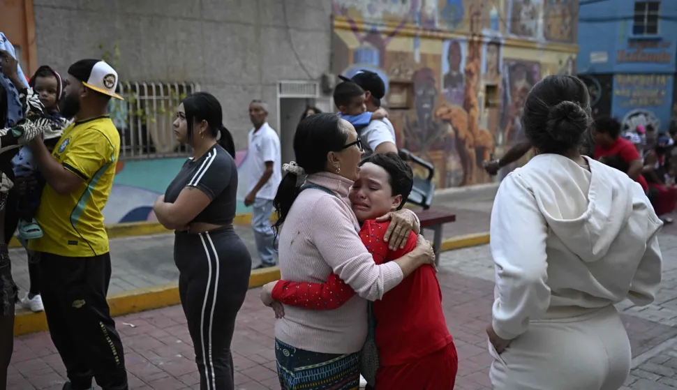 TOPSHOT - A woman comforts a child in the street following an earthquake in Caracas on June 24, 2026. Two earthquakes of magnitude 7.2 and 7.5 struck the same area of Venezuela on the evening of June 24, causing buildings to collapse, according to the United States Geological Survey (USGS) and AFP journalists. The quakes drove residents of the capital, Caracas, into the streets. (Photo by Federico PARRA/AFP)