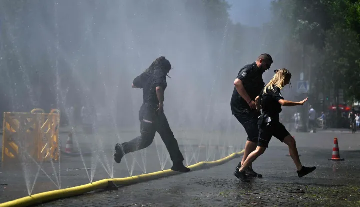 Employees of the public order office run over water hoses spilling water to provide relief from the summer heat as part of Cologne?s climate adaptation measures in Cologne, western Germany on June 25, 2026 during a heatwave in Europe. A heatwave sweeping Europe was starting to peak in Germany on June 25, 2026, with several open-air events cancelled and temperatures expected to top 40C through the weekend. Large parts of the country are already under "severe to extreme heat stress" with temperatures soaring to around 37C, the German Weather Service (DWD) said. (Photo by Ina FASSBENDER/AFP)