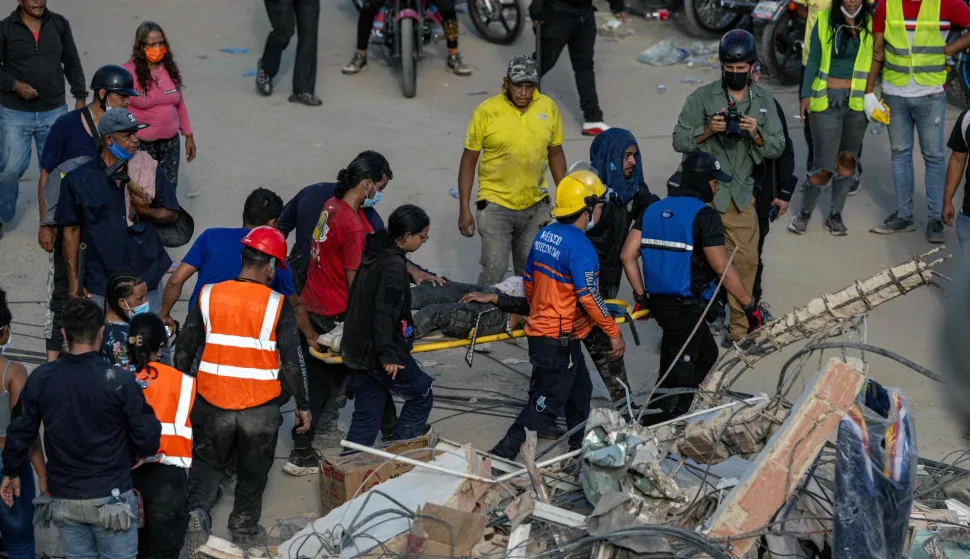 Rescuers and volunteers carry a person on a stretcher after being pulled alive from the rubble of a collapsed building in Caraballeda, La Guaira state, Venezuela, on June 28, 2026, following earthquakes. Thousands of rescuers, relatives and volunteers dig day and night through mounds of concrete to find survivors of the earthquakes that struck Venezuela more than three days ago, leaving nearly 1,500 dead and tens of thousands missing. (Photo by Miguel MEDINA/POOL/AFP)