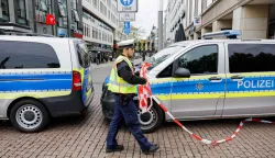 A police officer removes the police cordon at the entrance to the pedestrian zone of the Grimmaische Strasse in Leipzig, eastern Germany, close to the site where a car ploughed into people, leaving at least two dead and several injured, one day after the incident, on May 5, 2026. A man suspected of ploughing a car into a crowd in the eastern German city of Leipzig, killing two people, recently underwent treatment in a psychiatric hospital, the authorities said on May 5. The German national allegedly drove the vehicle on May 4 at high speed down a main street in the historic centre of the eastern city, leaving two people dead and many others wounded. The 33-year-old suspect was arrested at the scene and officials have said they do not believe he had a political or religious motive. (Photo by Jens SCHL?TER/AFP)